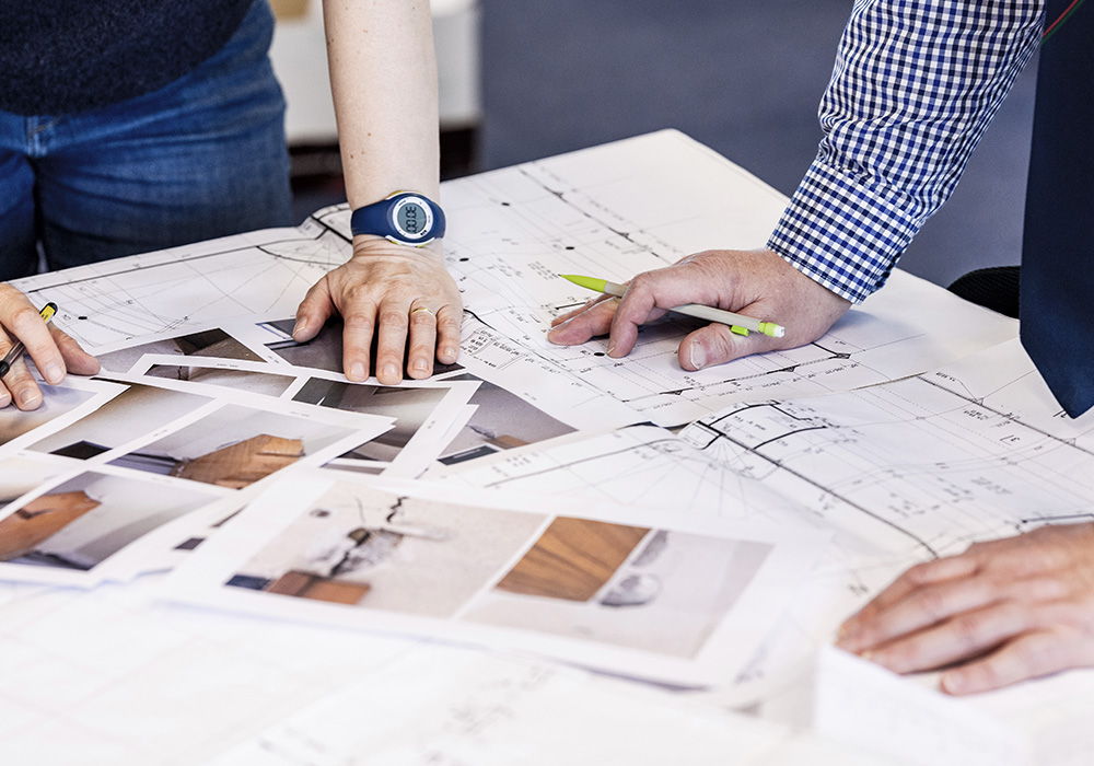 Deux personnes analysant plans et photo de design maison