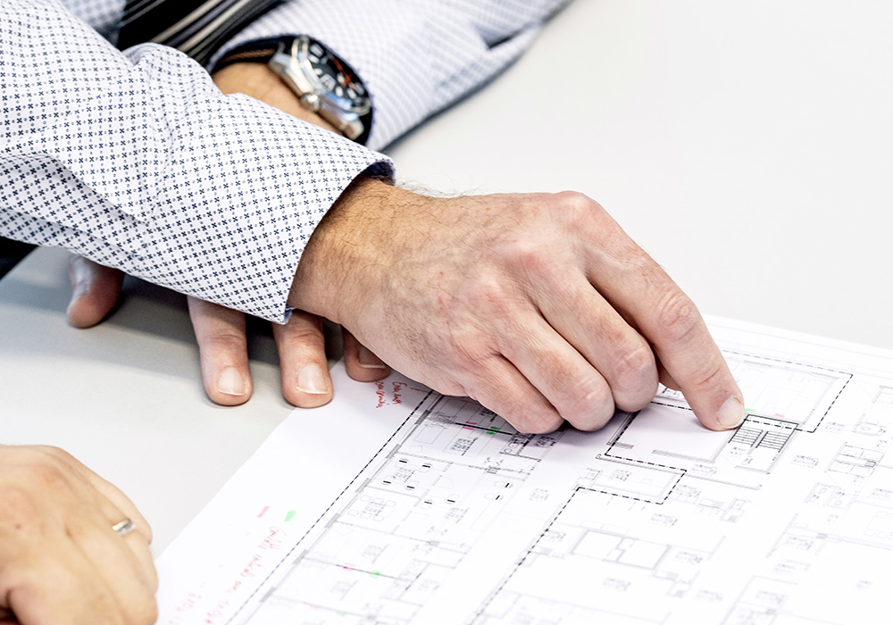 Hommme chemise montre pointe du doigt un élément d'un plan